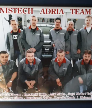 Bild av bilverkstedteam med ansatte i uniform foran en bil.