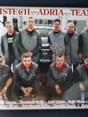 Bild av bilverkstedteam med ansatte i uniform foran en bil.