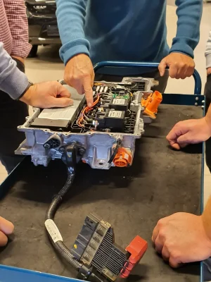 Detaljert bilde av biltekniker som jobber med elektrisk bilbatteri.